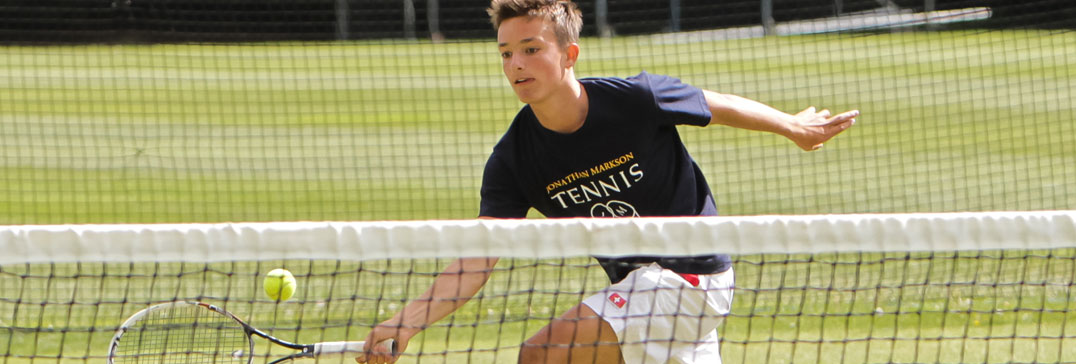 Jugador de tenis a la red en cancha de hierba